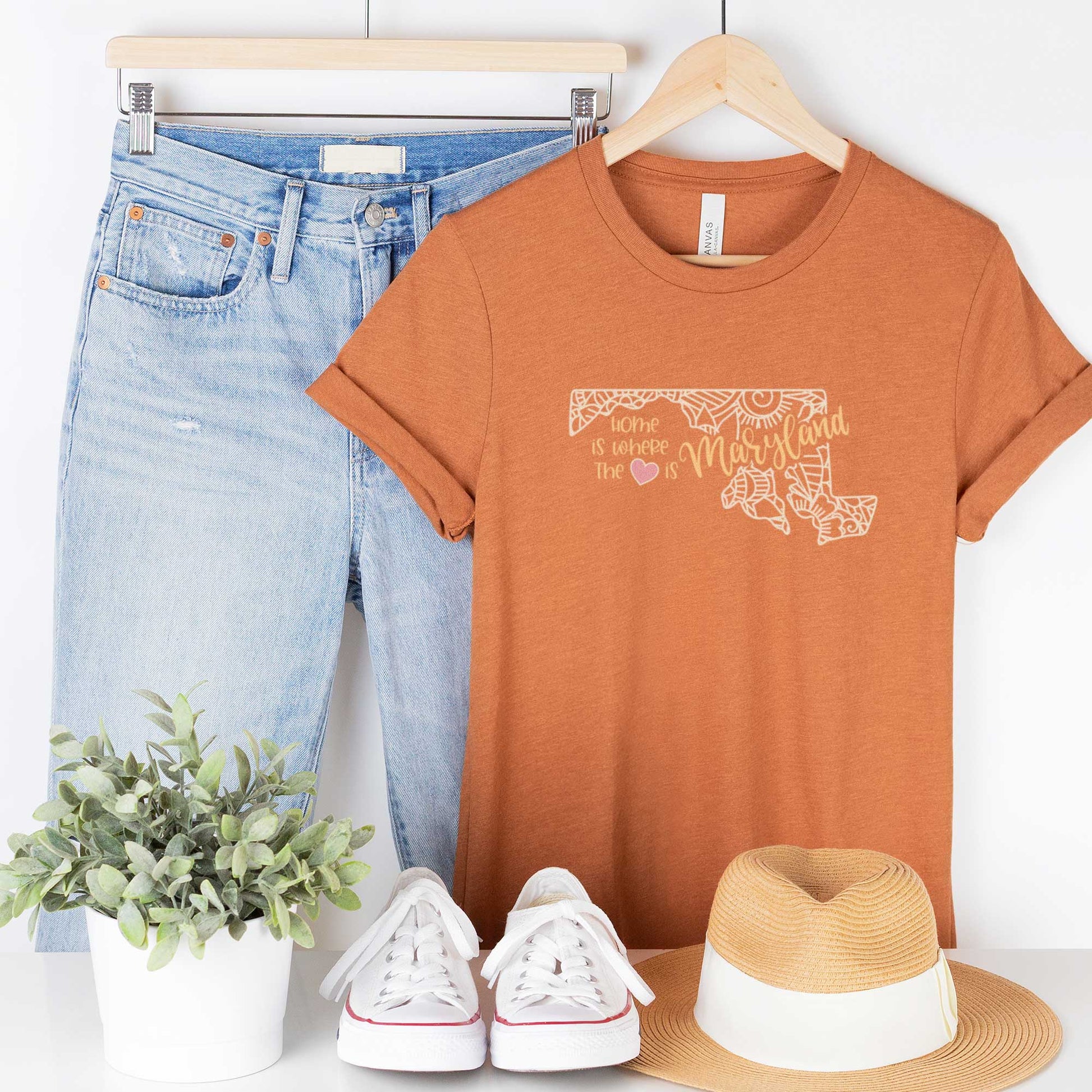A hanging heather autumn Bella Canvas t-shirt featuring a mandala in the shape of Maryland with the words home is where the heart is.