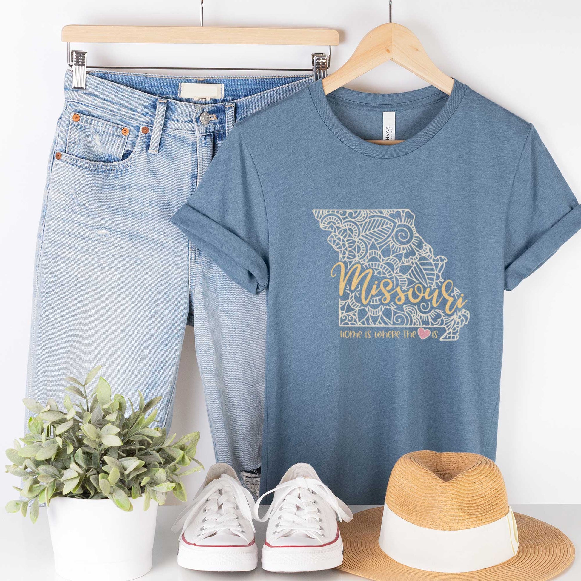 A hanging heather slate Bella Canvas t-shirt featuring a mandala in the shape of Missouri with the words home is where the heart is.