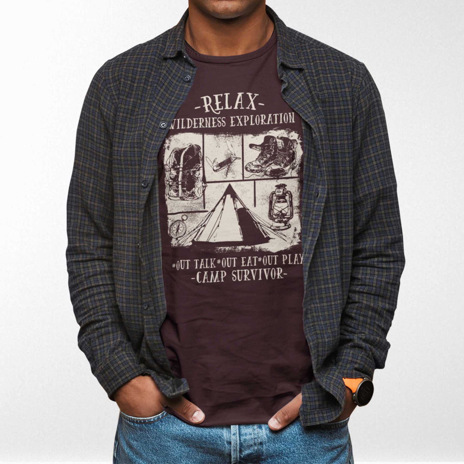 A man wearing an oxblood black Bella Canvas t-shirt featuring camping images with the words relax wilderness exploration, out talk, out eat, out play, camp survivor.