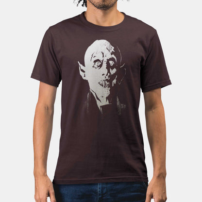 A man wearing an oxblood black Bella Canvas t-shirt featuring a bald vampire face and jutting teeth similar to Murnau's Nosferatu.