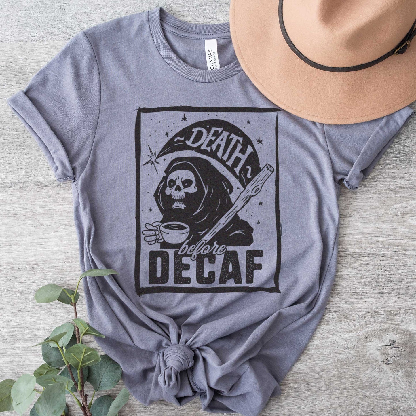 A storm gray Bella Canvas t-shirt featuring the grim reaper drinking a cup of coffee with the words Death before decaf