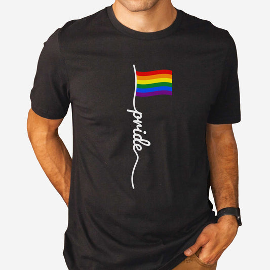 A man wearing a black Bella Canvas t-shirt featuring a LGBTQ rainbow flag with the words pride.