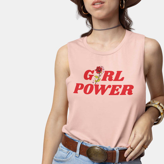 A woman wearing a peach Bella Canvas muscle tank featuring a rose with the words girl power.