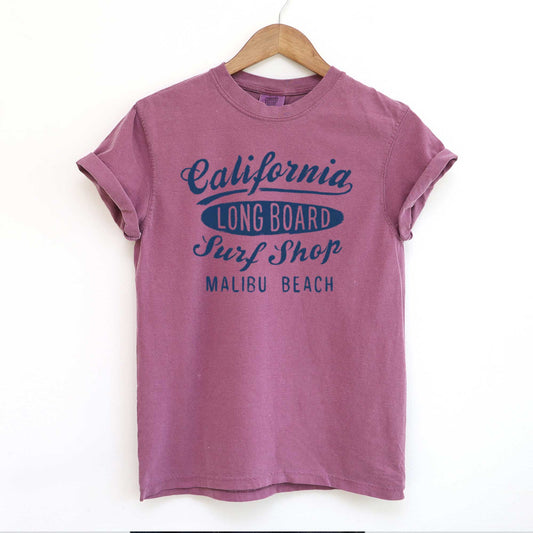 A hanging berry purple Comfort Colors t-shirt that says California long board surf shop Malibu Beach