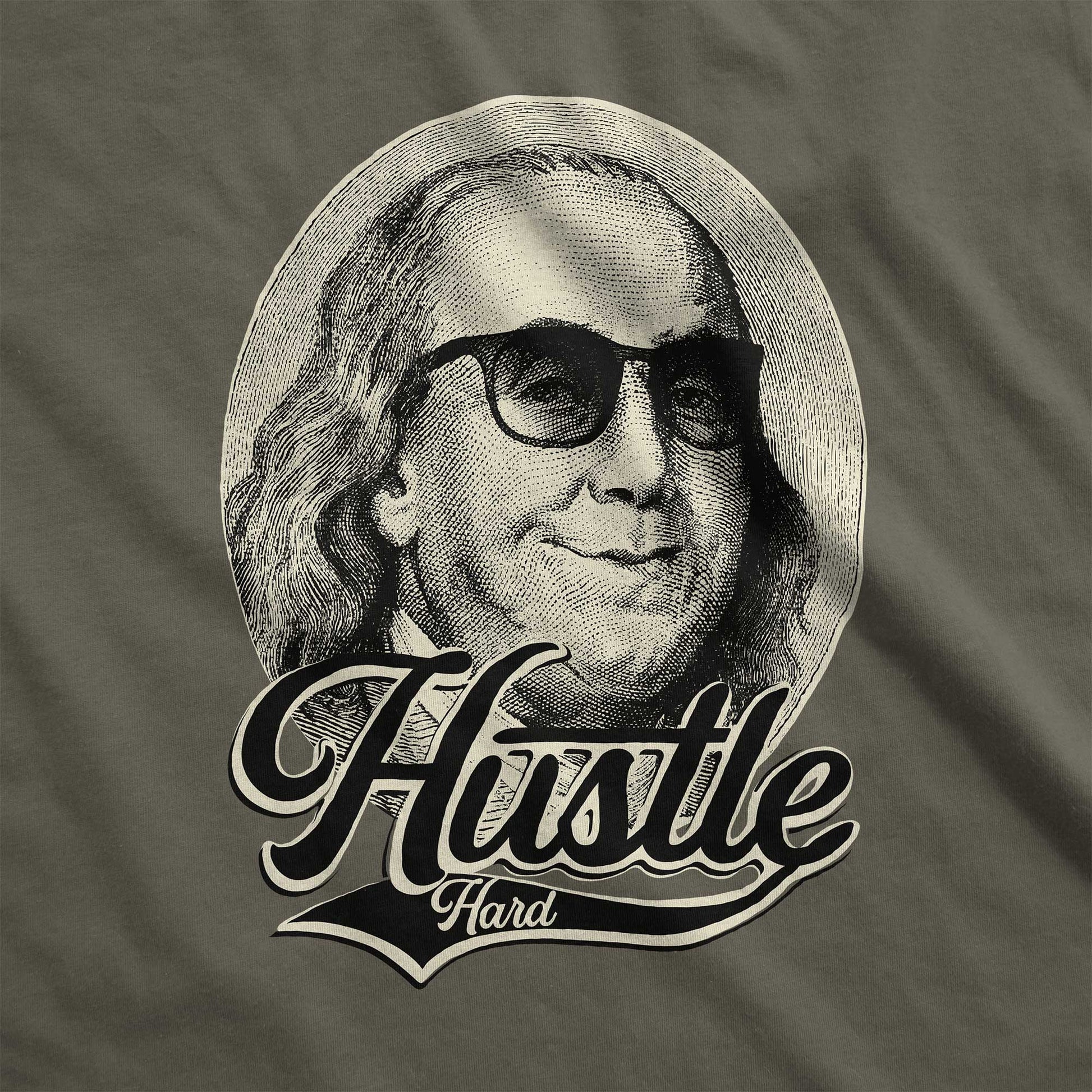 An army green Bella Canvas swatch that features Benjamin Franklin in sunglasses with the words hustle hard.