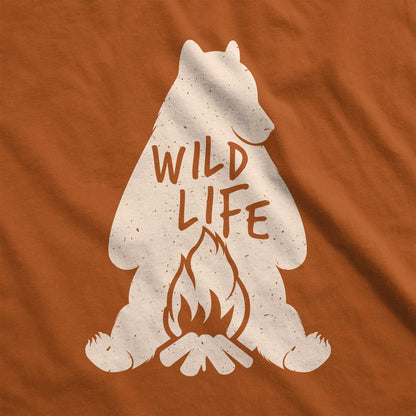 An autumn burnt orange Bella Canvas t-shirt featuring a silhouette of a grizzly bear sitting in front of a campfire with the words wild life.