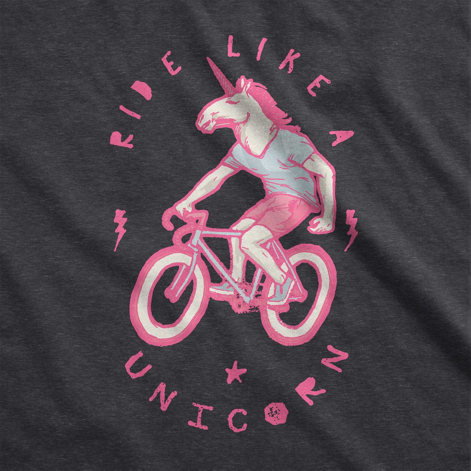 A dark grey heather Bella Canvas swatch featuring a neon pink unicorn riding a bike and the words ride like a unicorn.