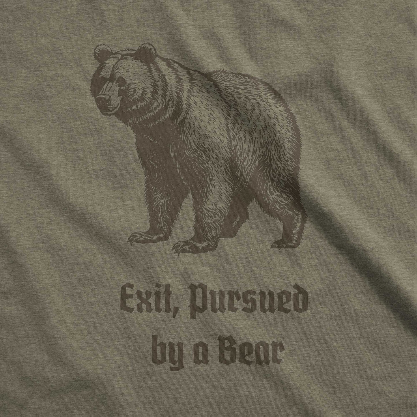 A heather olive Bella Canvas swatch featuring a vintage looking bear with the words exit, pursued by a bear.