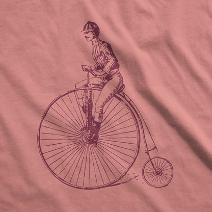 A heather mauve Bella Canvas swatch featuring a Victorian man riding a penny farthing bicycle.