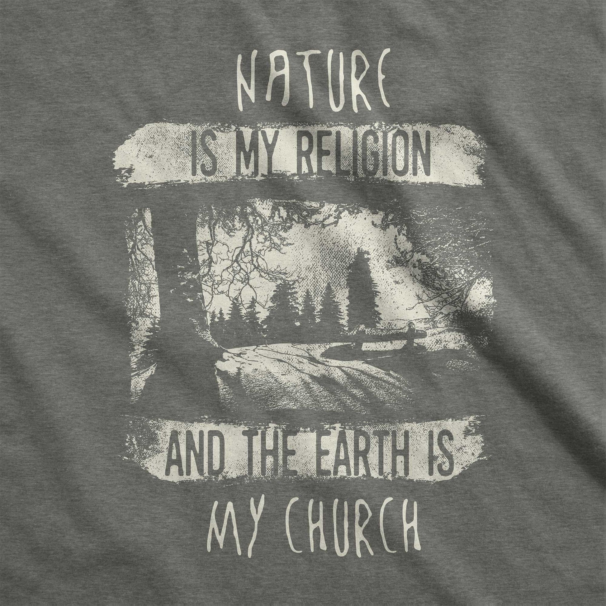 A heather military green Bella Canvas swatch featuring fields and a forest with the words nature is my religion and the earth is my church.