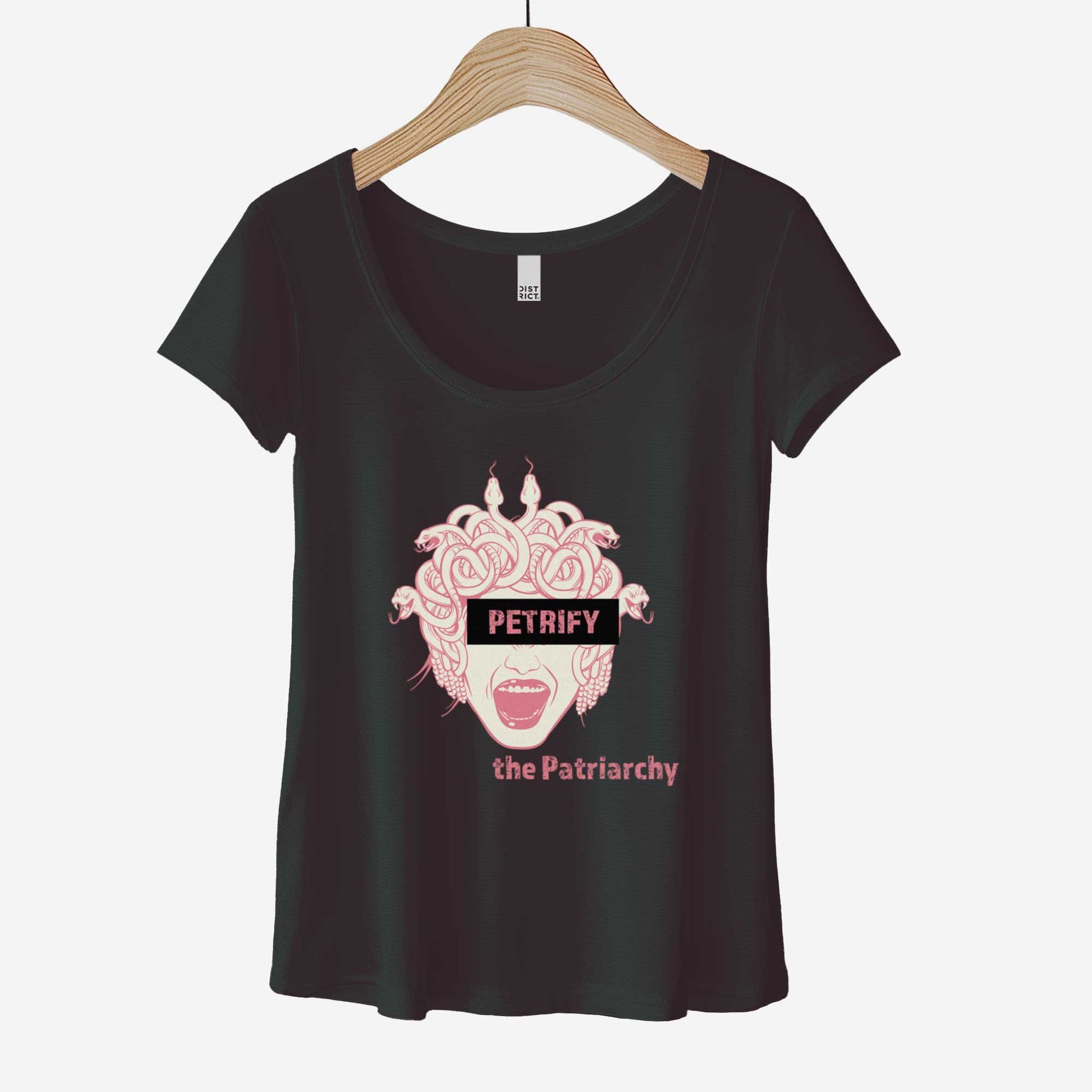 A hanging black District 7501 scoop neck t-shirt featuring the face of Medusa with a block of letters over here eyes that says petrify and the words the patriarchy below.