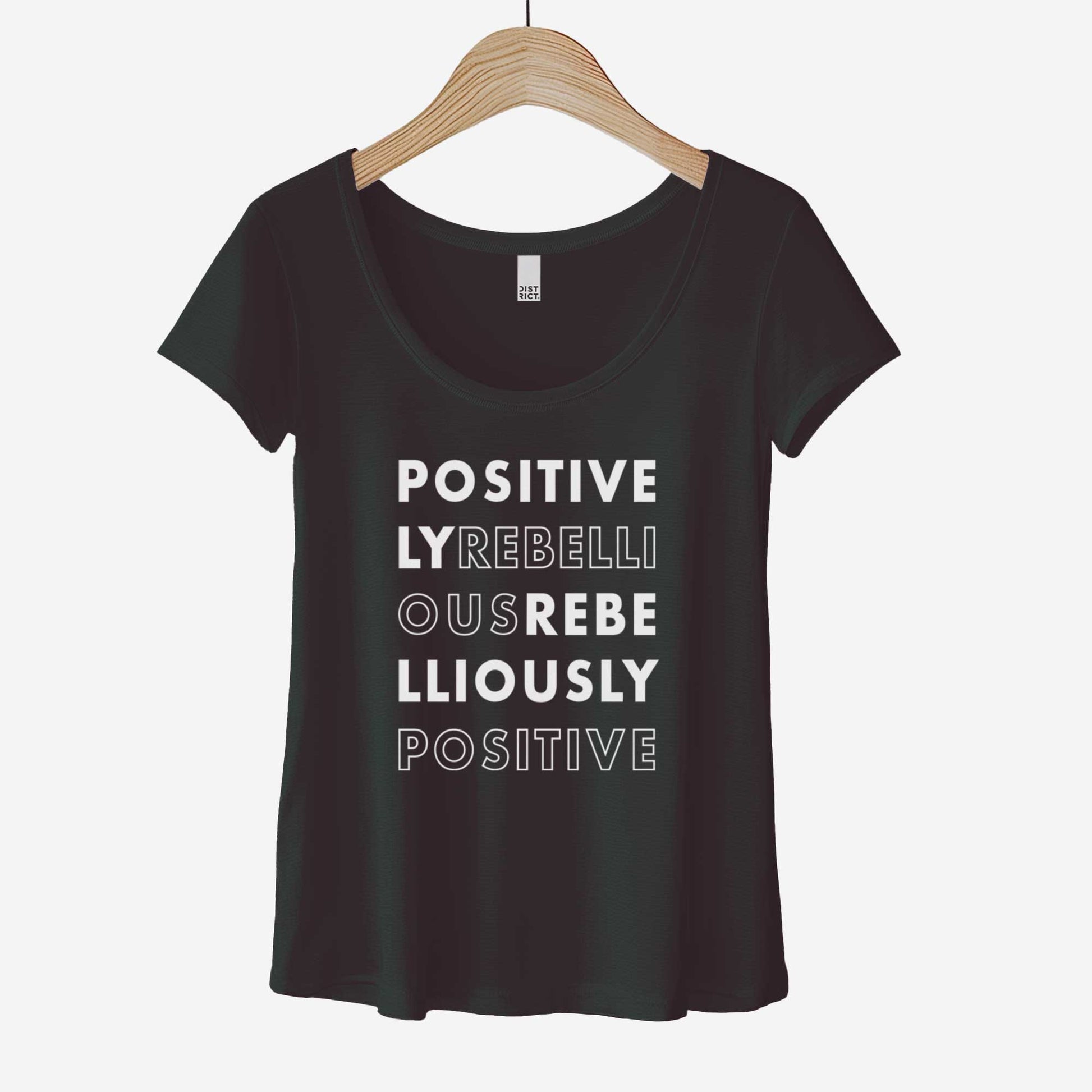A hanging black District 7501 scoop neck t-shirt featuring the words positively rebellious rebelliously positive.