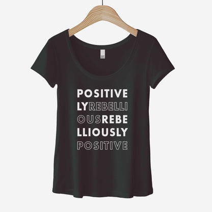 A hanging black District 7501 scoop neck t-shirt featuring the words positively rebellious rebelliously positive.