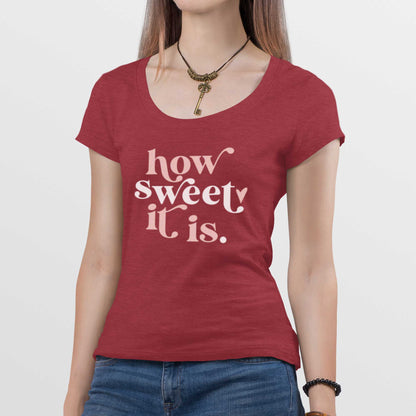 A woman wearing a heathered red District scoop t-shirt featuring the words how sweet it is.