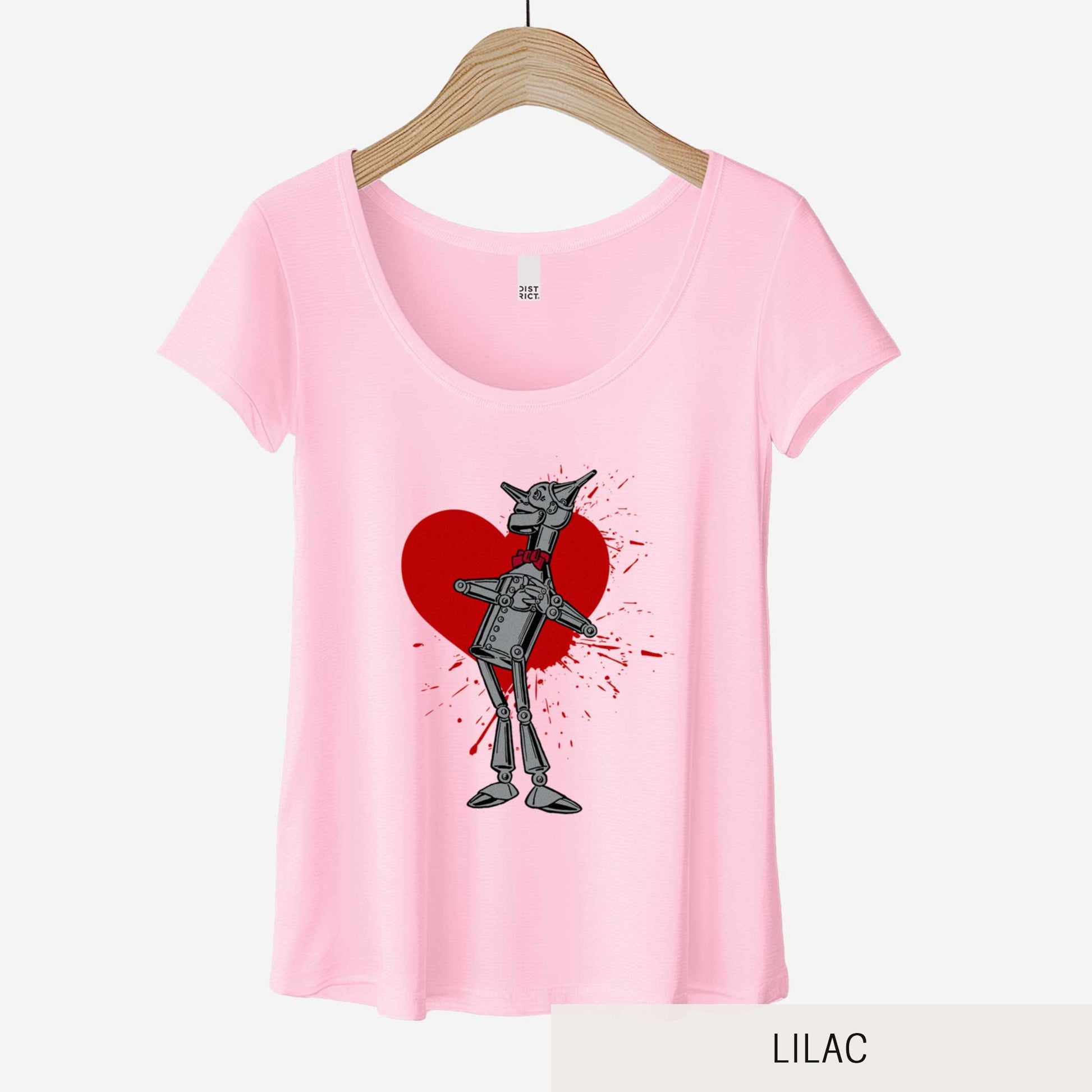 A hanging lilac District 7501 scoop neck t-shirt featuring a vintage Denslow illustration of the tin man from the Wizard of Oz with a heart symbol spattered behind him.