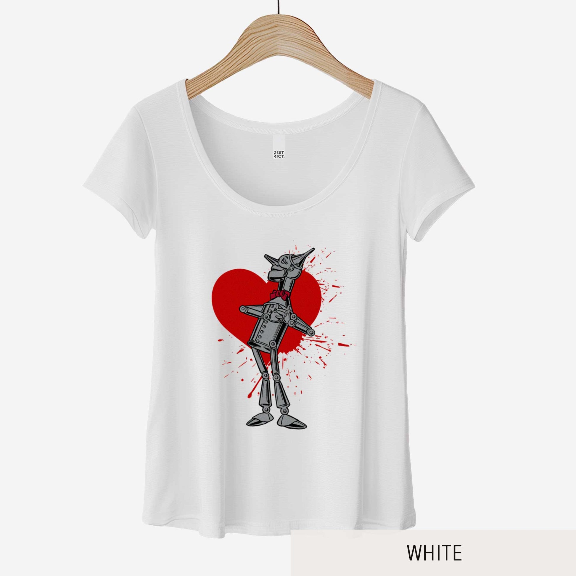 A hanging white District 7501 scoop neck t-shirt featuring a vintage Denslow illustration of the tin man from the Wizard of Oz with a heart symbol spattered behind him.