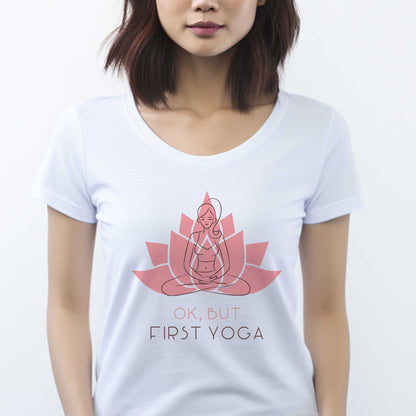 A woman wearing a white District 7501 t-shirt featuring a woman in the yoga lotus pose overlayed on top of a lotus flower and the words ok but first yoga.