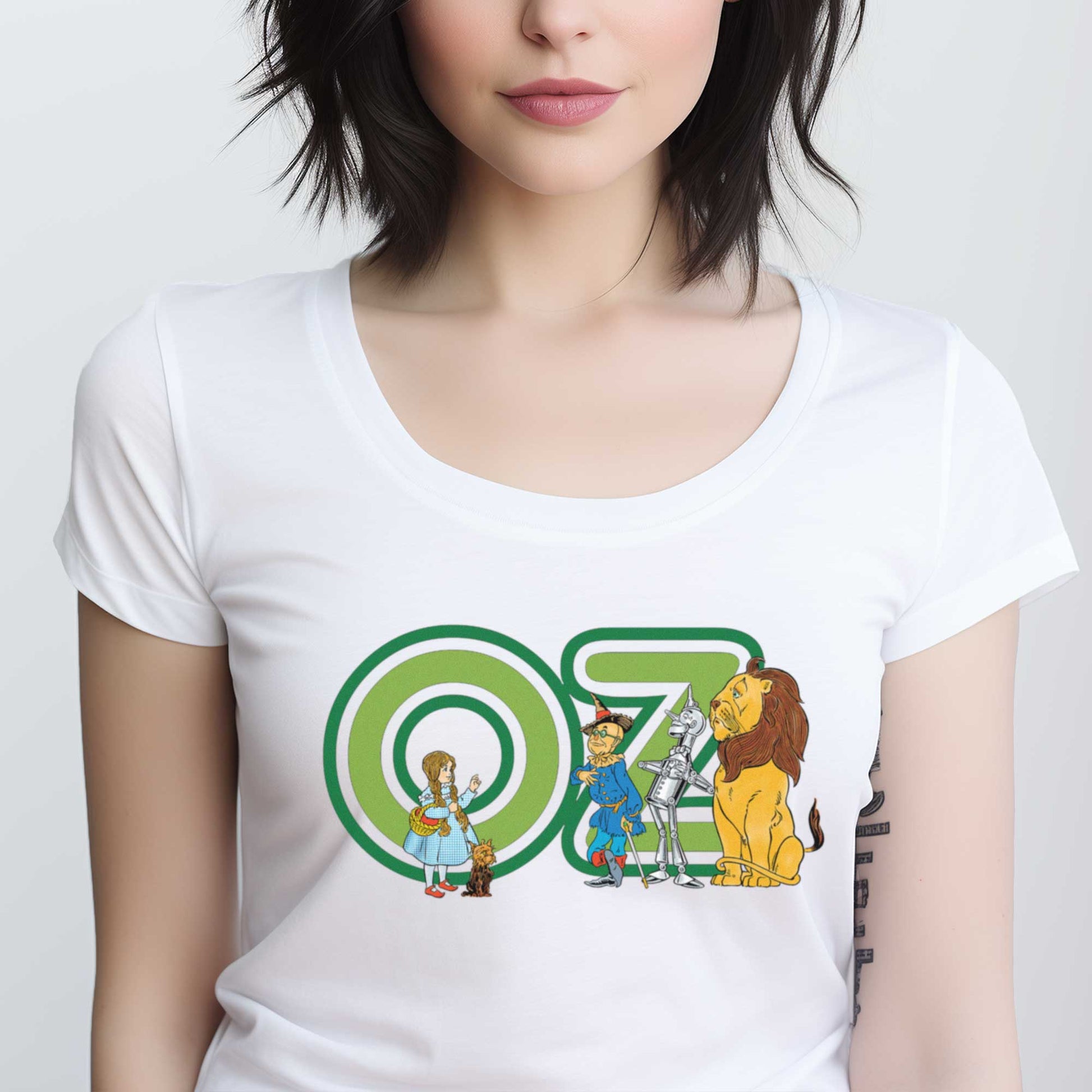 A woman wearing a white District 7501 t-shirt featuring W.W. Denslow's classic illustrations of Dorothy, the Scarecrow, the Tinman and the Cowardly Lion.