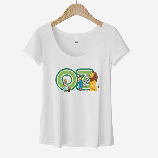 A hanging white District 7501 scoop neck t-shirt featuring W.W. Denslow's classic illustrations of Dorothy, the Scarecrow, the Tinman and the Cowardly Lion.