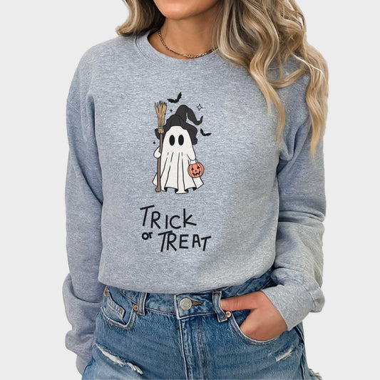A woman wearing a sport grey Gildan sweatshirt featuring a cute cartoon witch ghost with the words trick or treat.