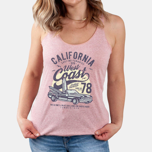 A woman wearing a desert pink Next Level racerback tank featuring a vintage convertible car with a surfboard and sunset and the words california west coast.