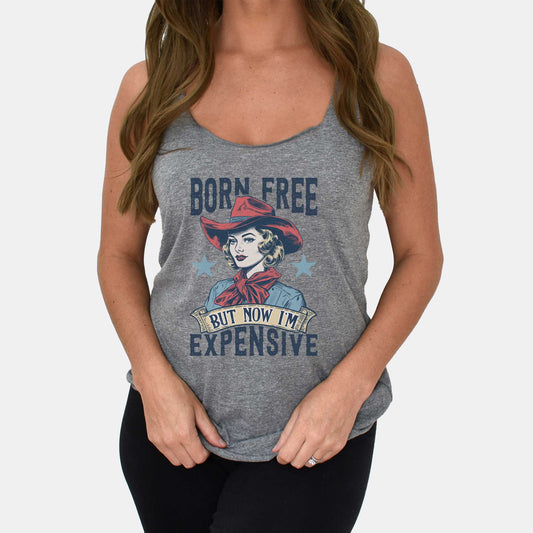 A woman wearing a premium heather Next Level racerback tank featuring a retro cowgirl with the words born free but now i'm expensive.