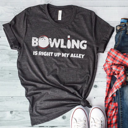 A dark grey heather Bella Canvas t-shirt that says bowling is right up my alley with a bowling ball and pin.