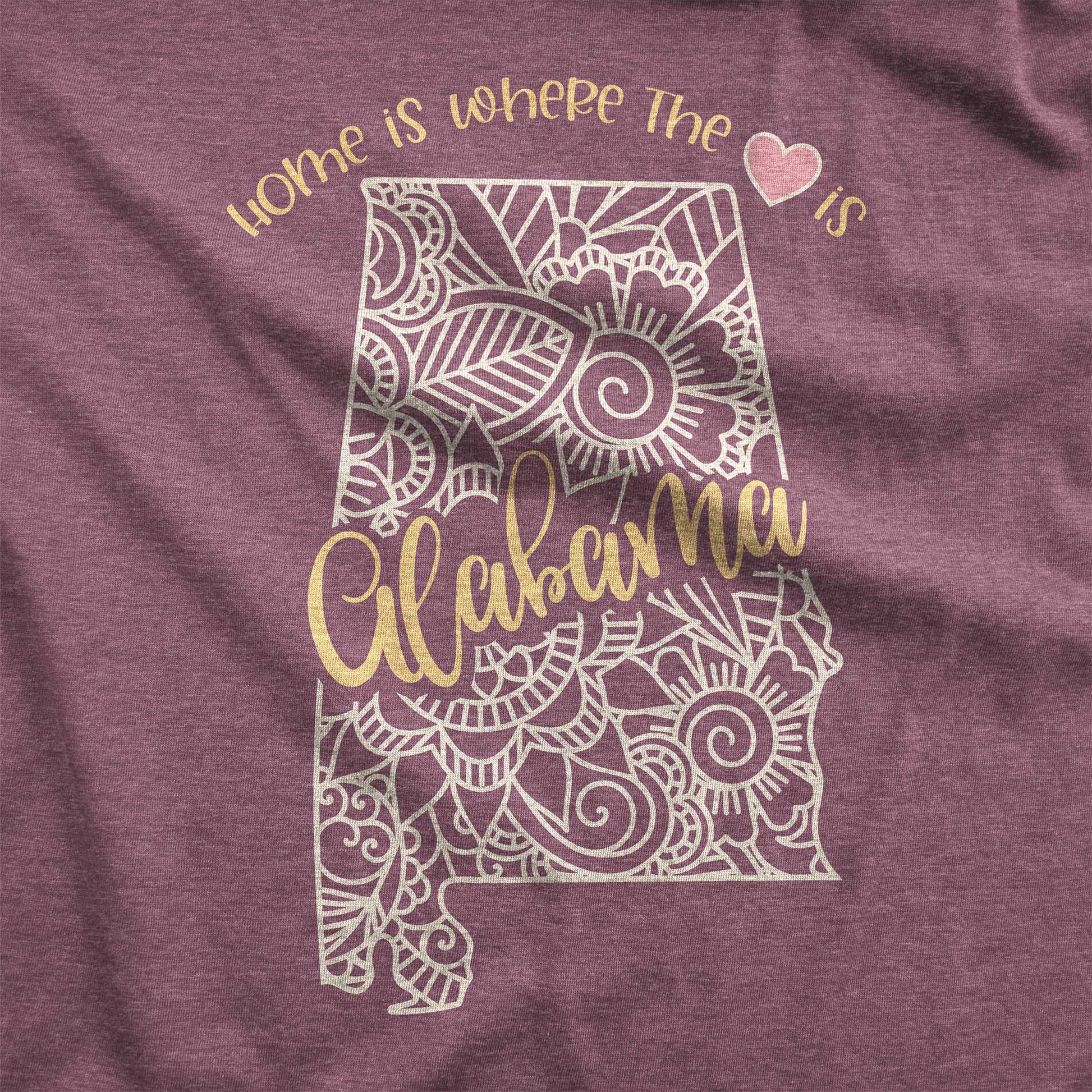 A heather maroon Bella Canvas swatch featuring a mandala in the shape of Alabama with the words home is where the heart is.