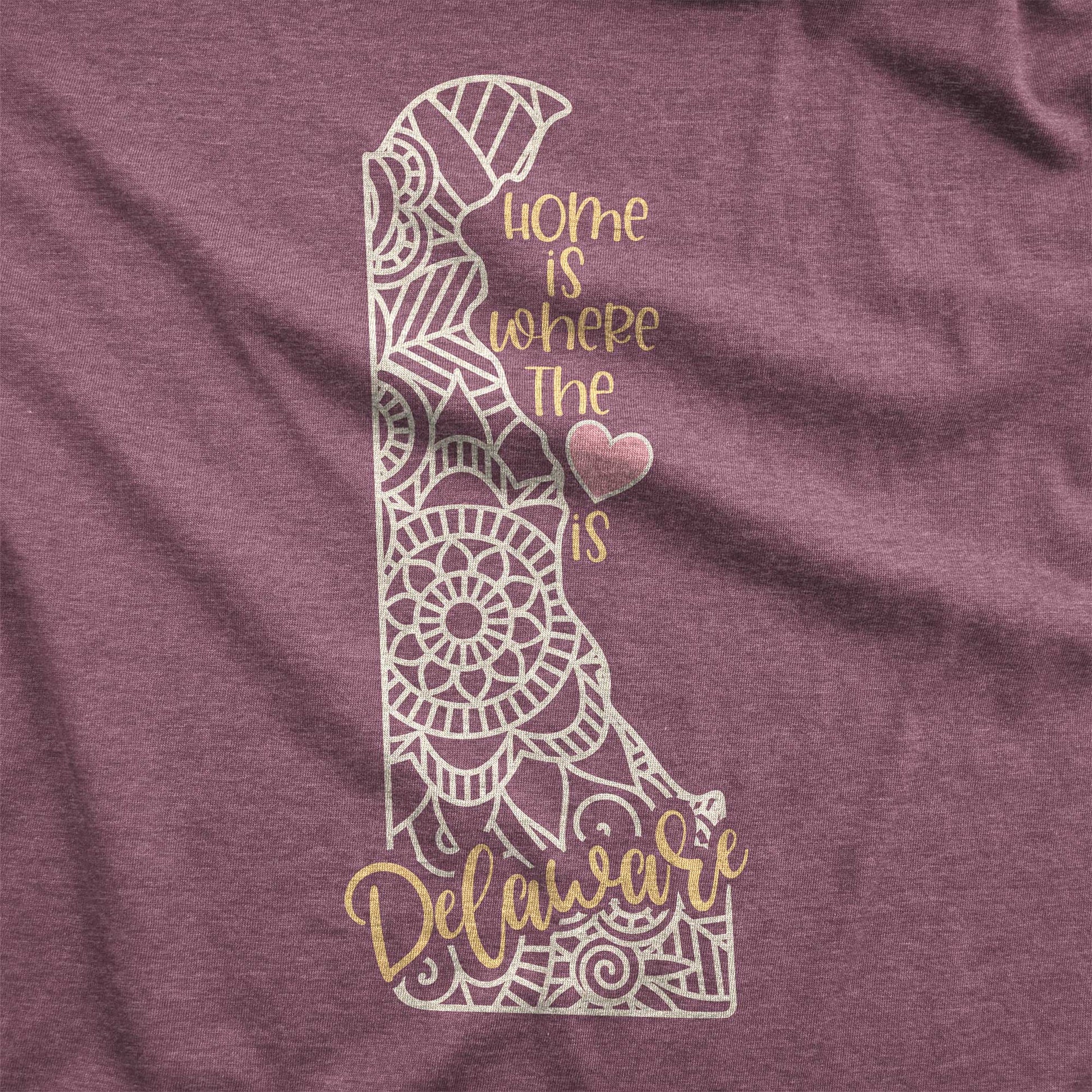 A heather maroon Bella Canvas swatch featuring a mandala in the shape of Delaware with the words home is where the heart is.