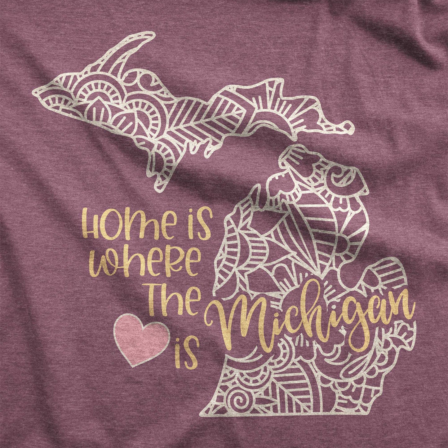 A heather maroon Bella Canvas swatch featuring a mandala in the shape of Michigan with the words home is where the heart is.