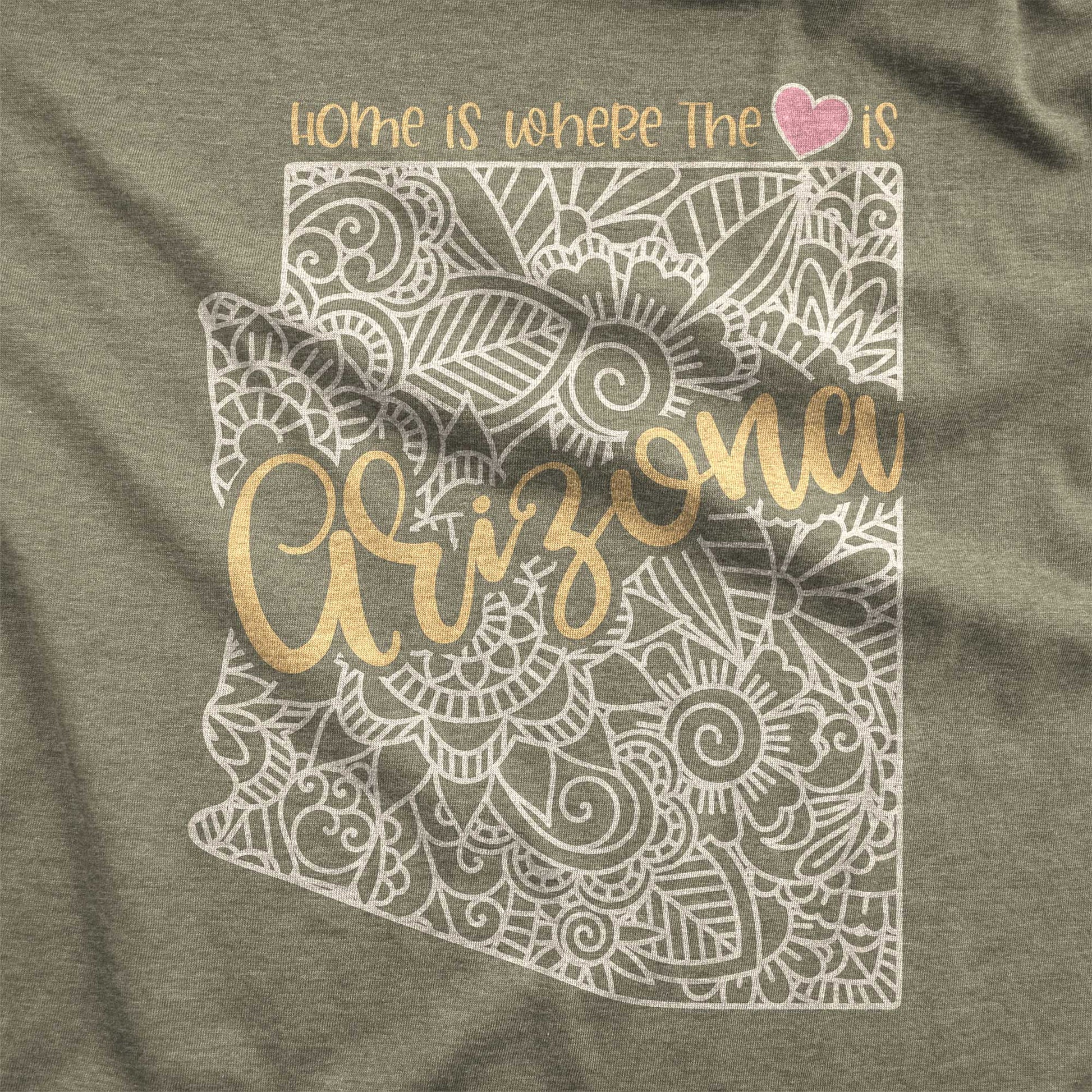 A heather olive Bella Canvas swatch featuring a mandala in the shape of Arizona with the words home is where the heart is.