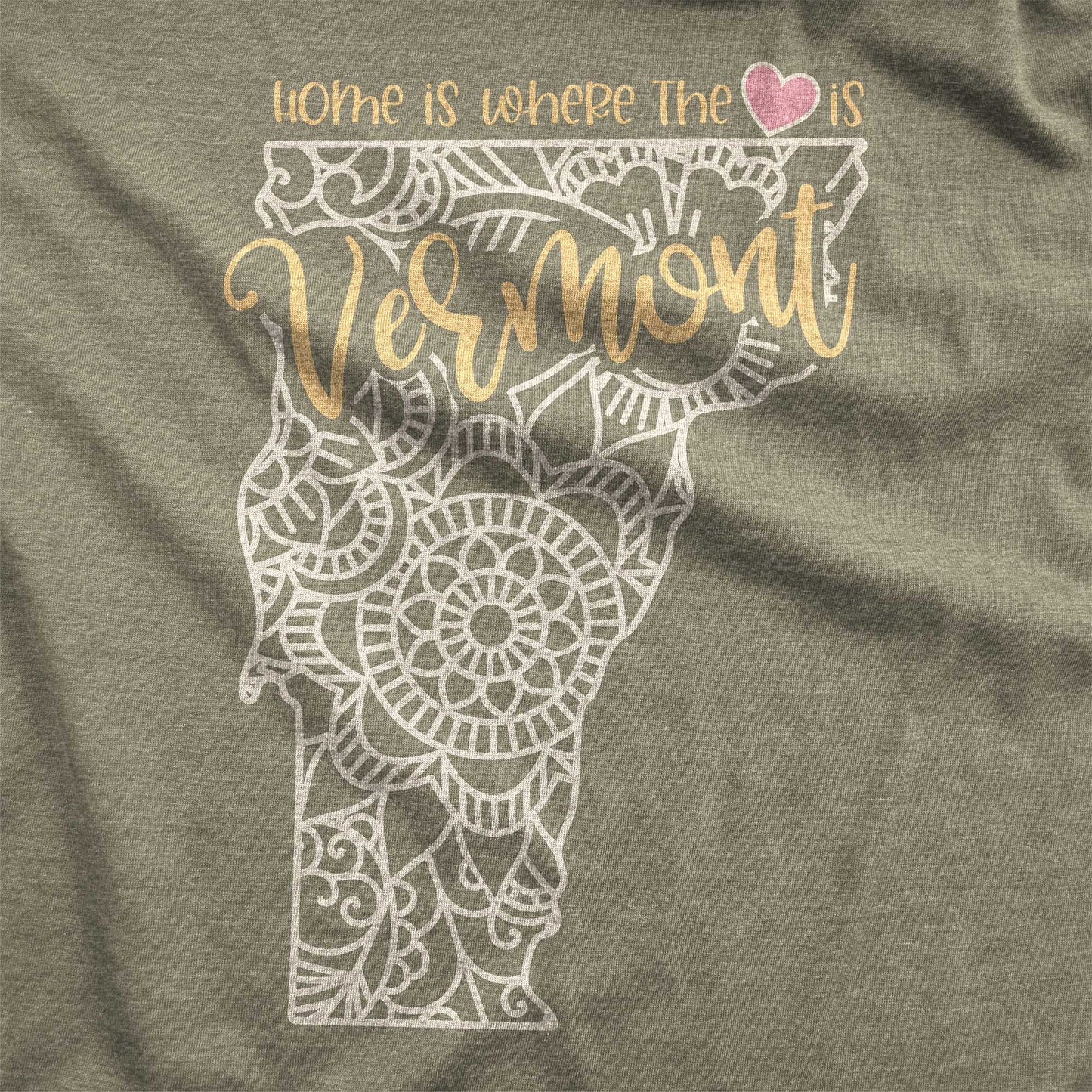 A heather olive Bella Canvas swatch featuring a mandala in the shape of Vermont with the words home is where the heart is.